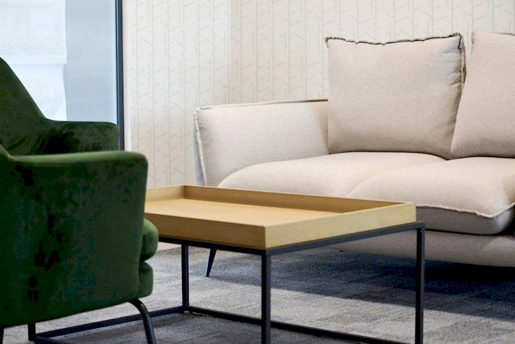 Contemporary lounge seating with upholstered sofa, green armchair and brass coffee table.