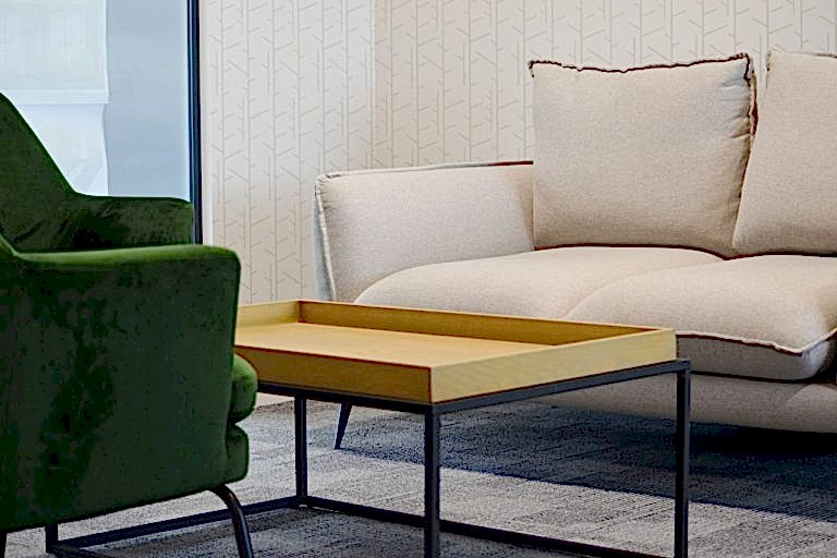 Contemporary lounge seating with upholstered sofa, green armchair and brass coffee table.