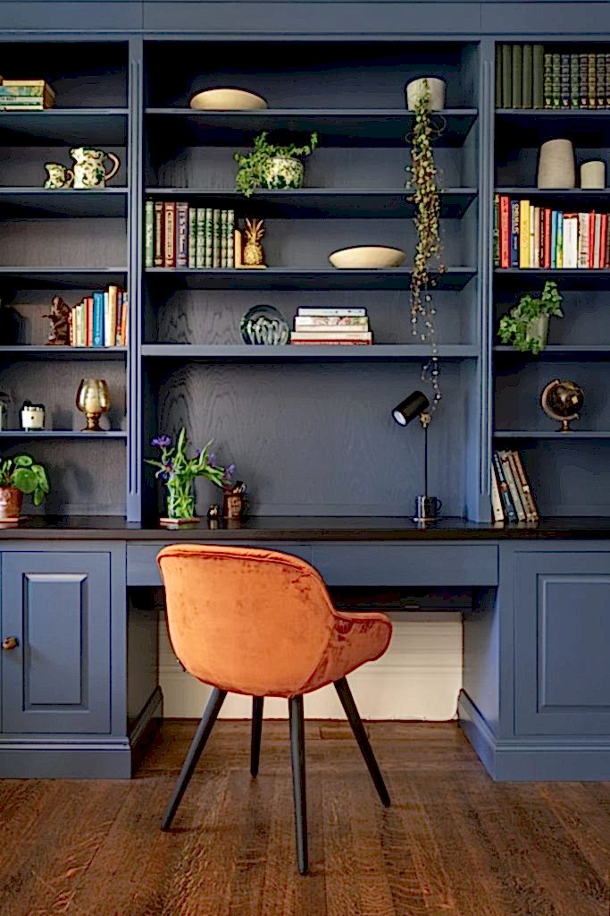 Contemporary workspace with bespoke blue shelving, styled bookcase, and rust velvet accent chair.